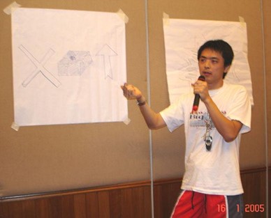 A younger Ka Hoe speaking beside a flipchart in a photo dated 2005